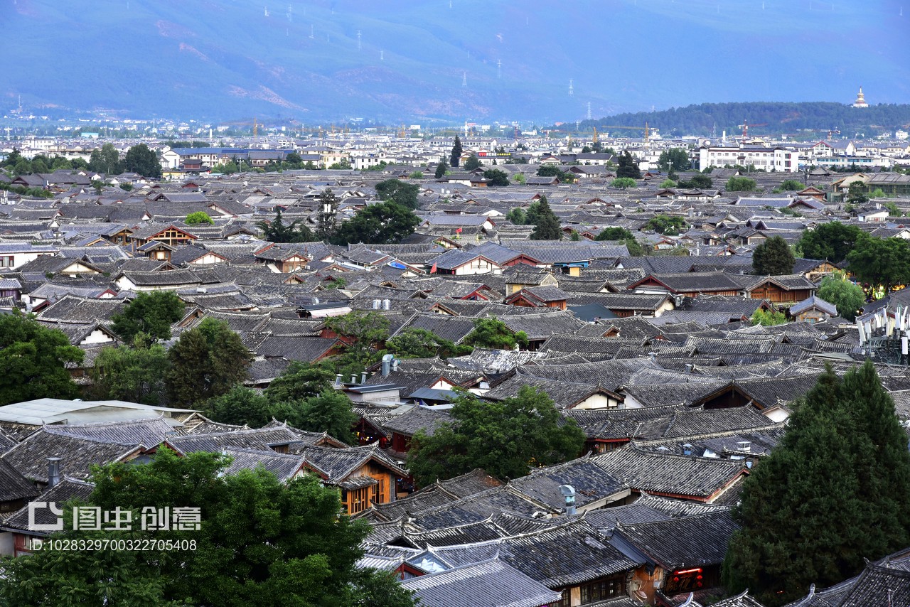 中国云南省丽江市丽江古城,傍晚,古城全景,夕阳西下,纳西族建筑的屋顶和远山,映在太阳光下。